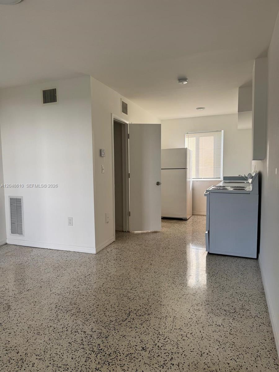 A kitchen with white appliances and speckled flooring is visible from an adjacent room — 680 NE 88th Ter # 2, Miami FL 33138, MIAMI, FL