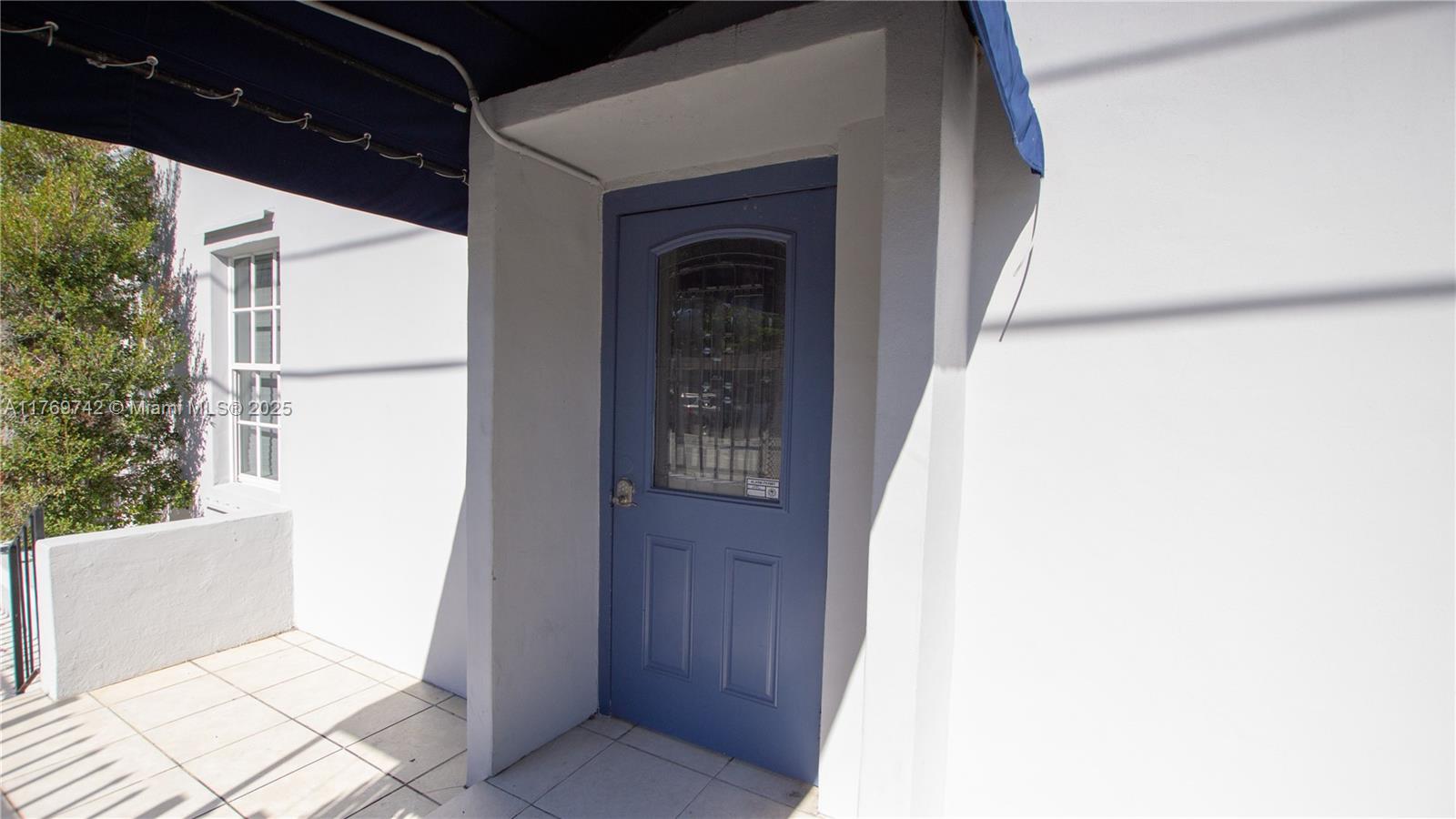 A blue door with a glass insert is set into a white exterior wall — 577 NE 62 STREET # 2, Miami FL 33138, MIAMI, FL
