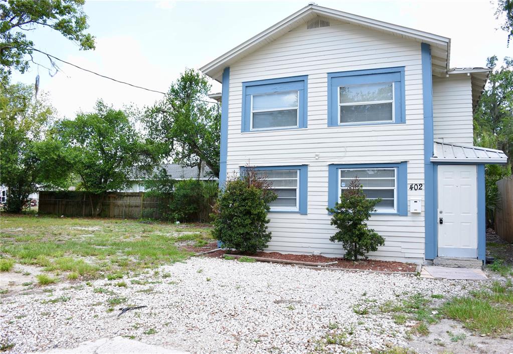 A two-story house with light siding, blue trim, and a gravel driveway in front — 402 LENOX STREET, LAKELAND, FL