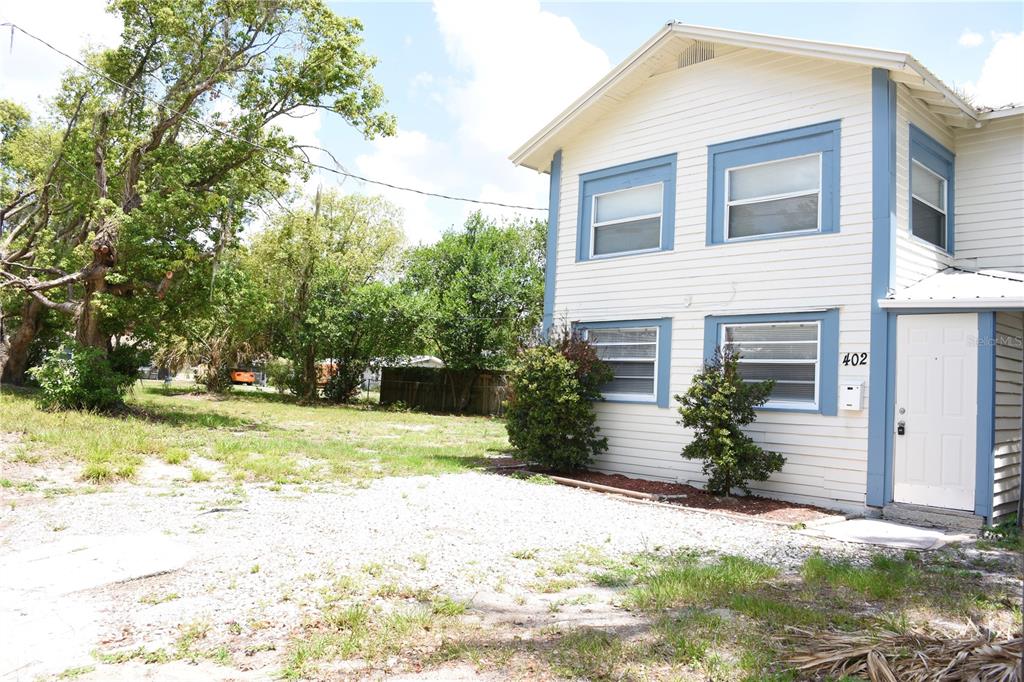 A two-story house with white siding and blue trim sits next to a gravel yard — 402 LENOX STREET, LAKELAND, FL