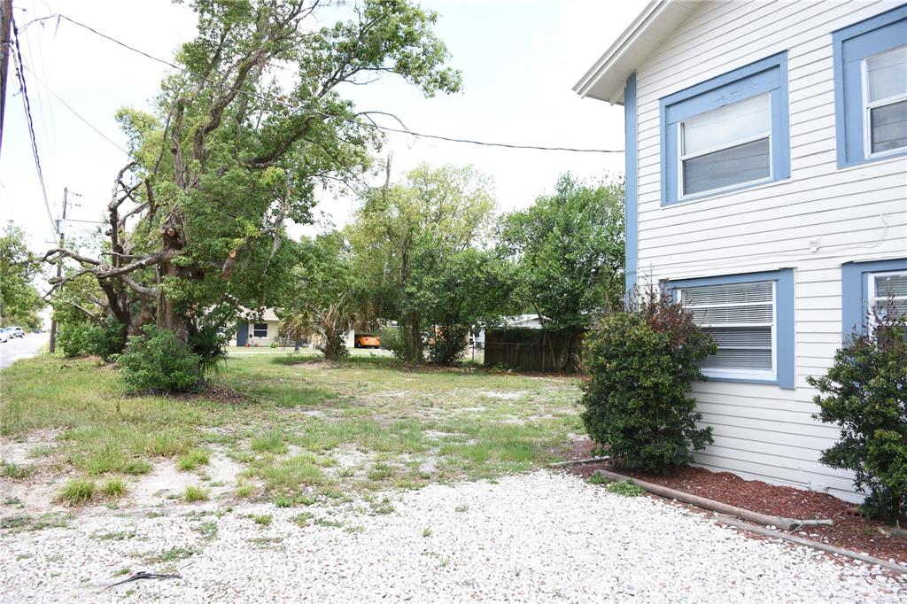 A side view of a white building with blue trim next to a gravel lot — 402 LENOX STREET, LAKELAND, FL
