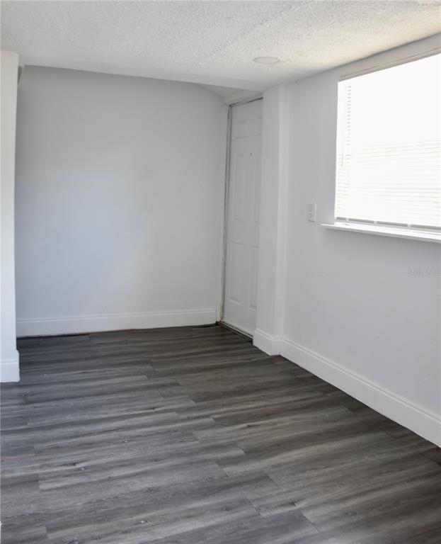 An empty room features white walls, a window with blinds, and gray wood-look flooring — 402 LENOX STREET, LAKELAND, FL