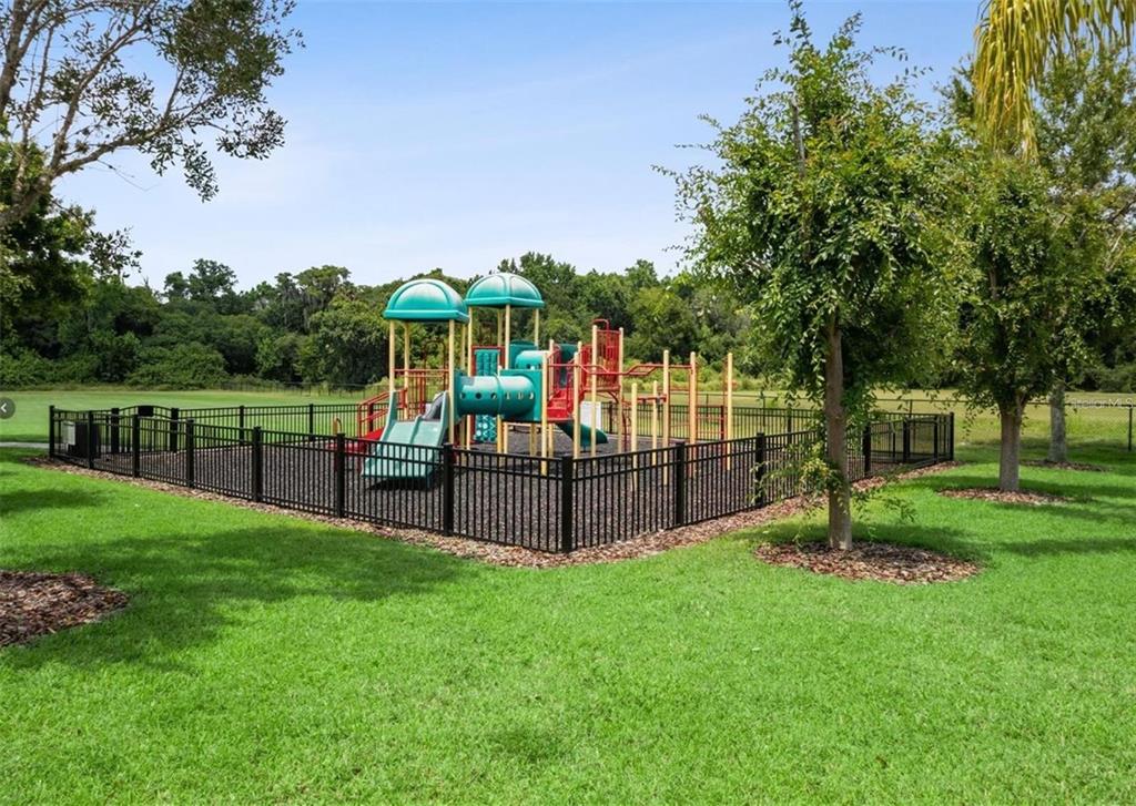 A fenced-in playground with climbing structures and slides sits on a grassy lawn — 420 MARATHON LANE, SANFORD, FL