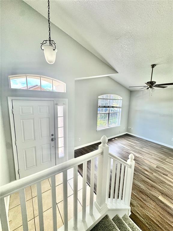 An entryway with a white door, vaulted ceilings, and a staircase leading to a living area — 420 MARATHON LANE, SANFORD, FL