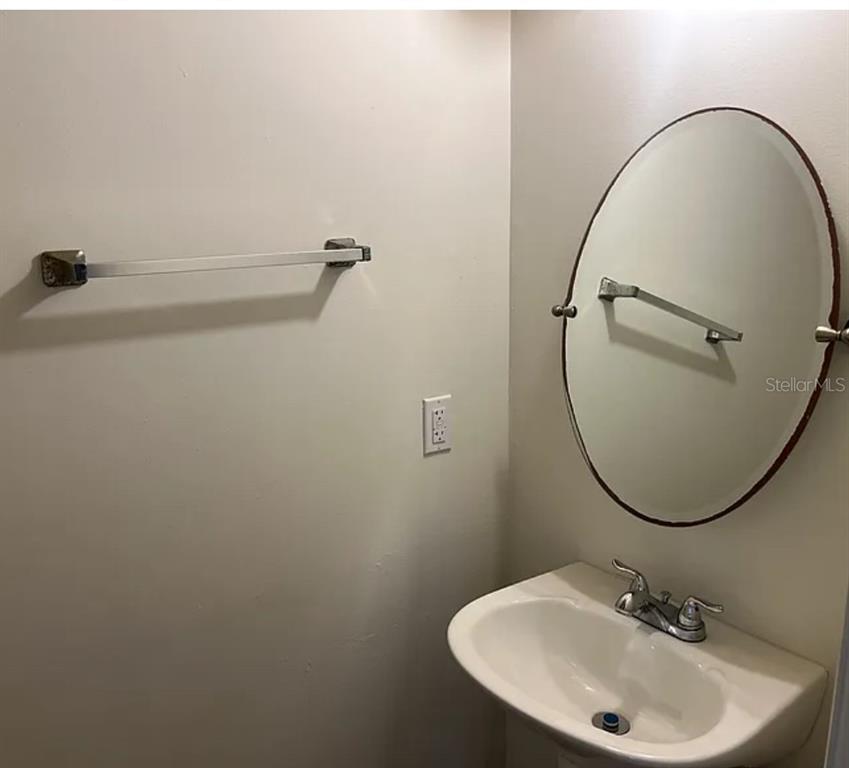 A small bathroom features a pedestal sink, an oval mirror, and a wall-mounted towel bar — 2302 MAKI ROAD UNIT 98, PLANT CITY, FL