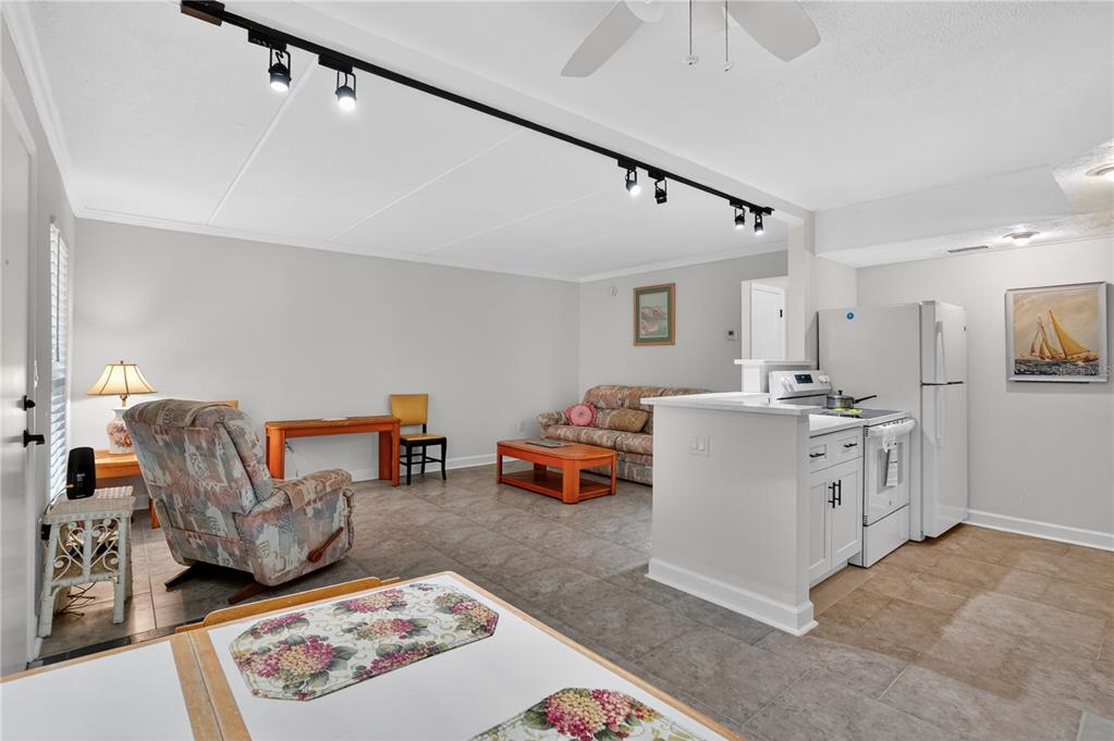 An open-concept living room and kitchen area with tile flooring and track lighting — 8931 BLIND PASS ROAD UNIT 156, ST PETE BEACH, FL