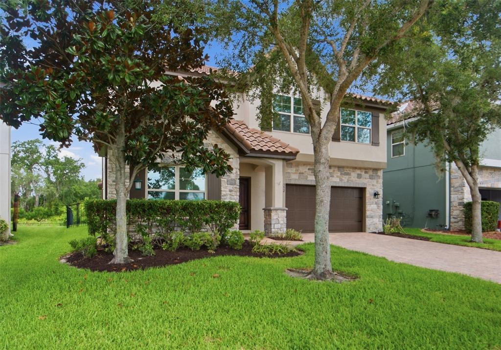 A two-story house with a stone facade, tile roof, and a two-car garage — 552 EGRET PLACE DRIVE, WINTER GARDEN, FL