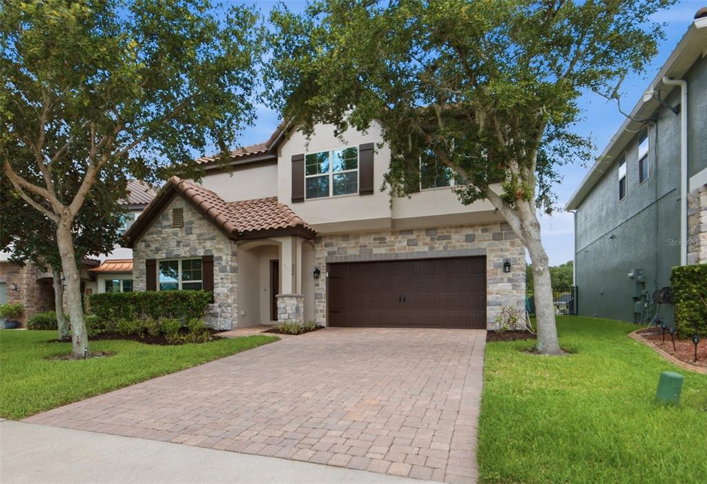 A two-story house with a stone facade, tile roof, and a paved driveway — 552 EGRET PLACE DRIVE, WINTER GARDEN, FL