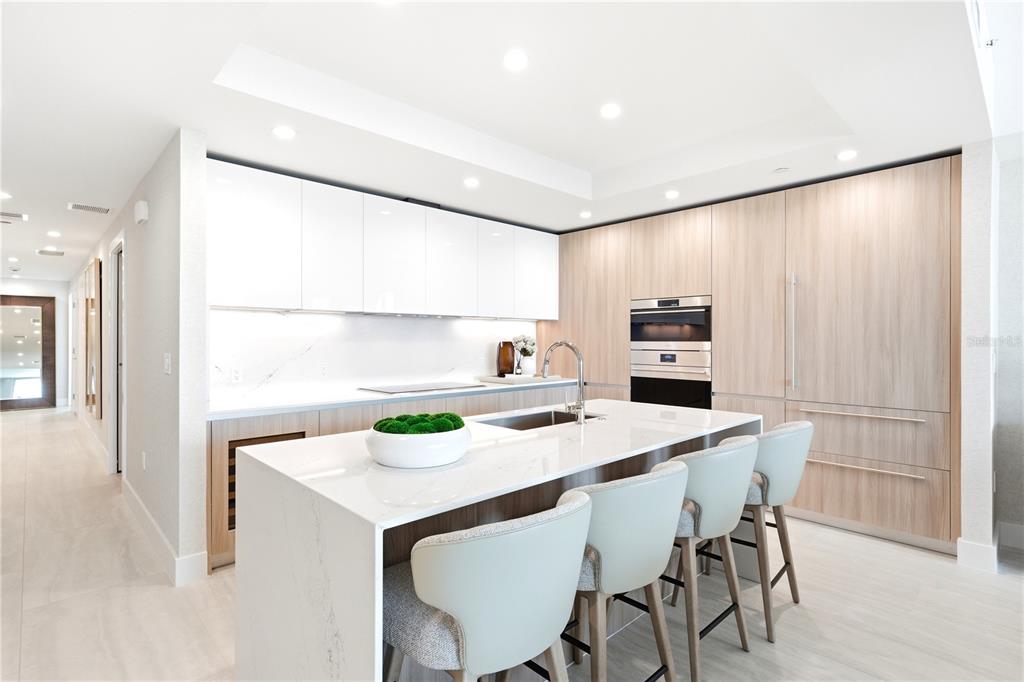 A modern kitchen features white upper cabinets, light wood lower cabinets, and a central island — 5713 BOWEN DANIEL DRIVE UNIT 703, TAMPA, FL