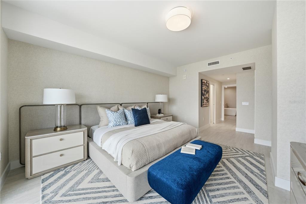 A modern bedroom features a king bed, blue accent bench, and patterned area rug — 5713 BOWEN DANIEL DRIVE UNIT 703, TAMPA, FL