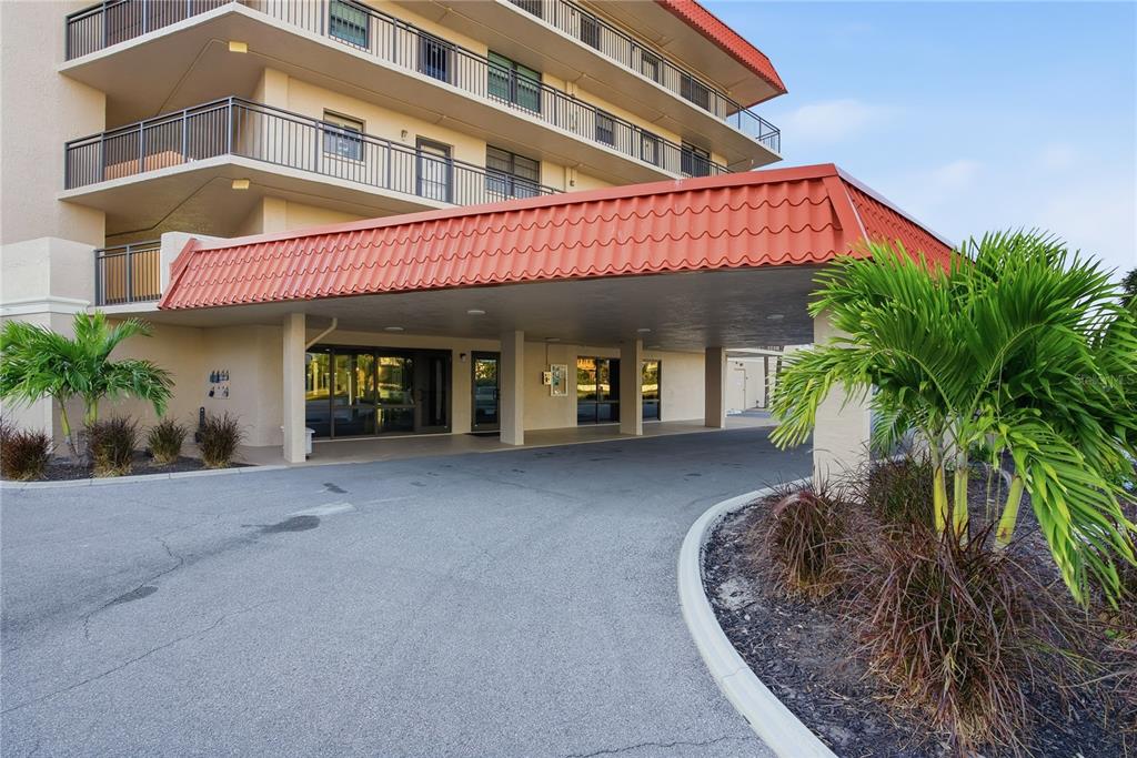 The exterior of a multi-story building features a covered entrance with a red tile roof — 17580 GULF BOULEVARD UNIT 302, REDINGTON SHORES, FL