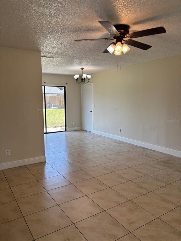 A living room with beige tile flooring, a ceiling fan, and a sliding glass door — 710 BUNKER LANE, POINCIANA, FL
