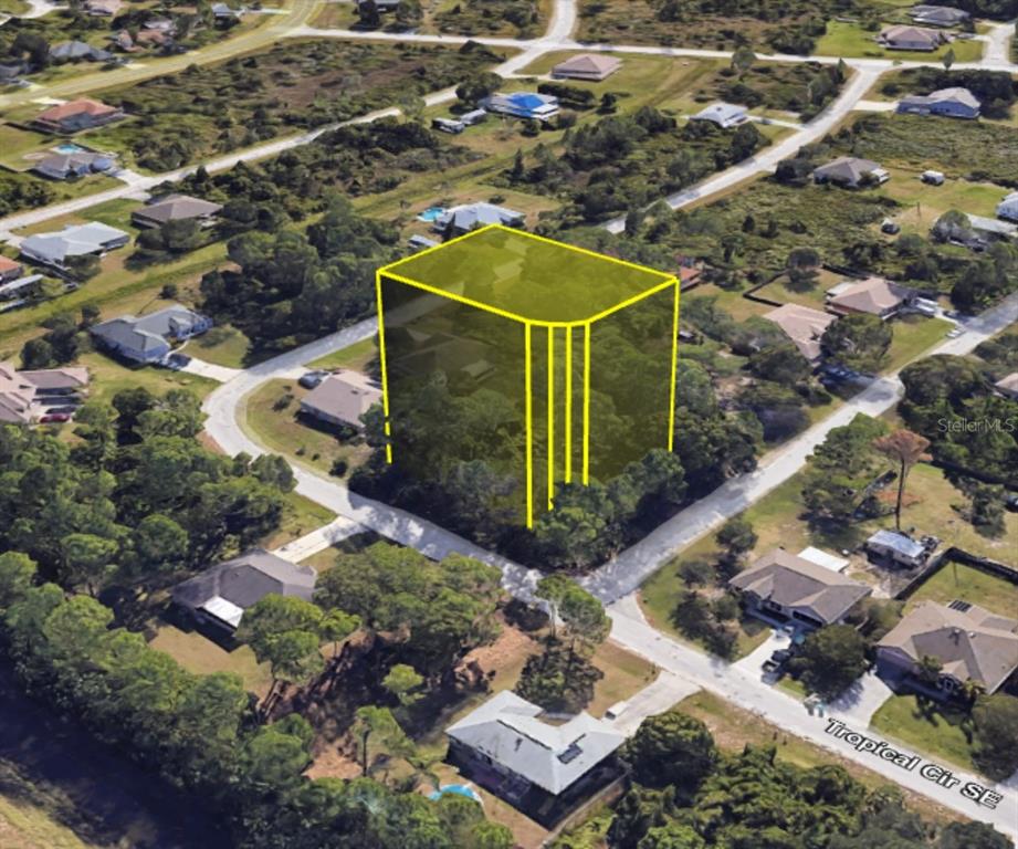 An aerial view shows a vacant, tree-covered residential lot highlighted by a yellow digital outline — SAN SALVADOR AVENUE SE, PALM BAY, FL