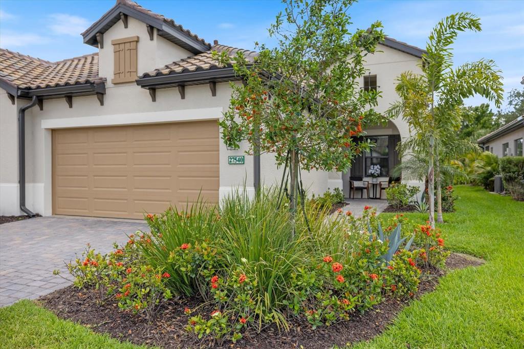 A single-story house exterior features a tan garage, a landscaped front garden, and a porch — 27540 JANZEN COURT, ENGLEWOOD, FL