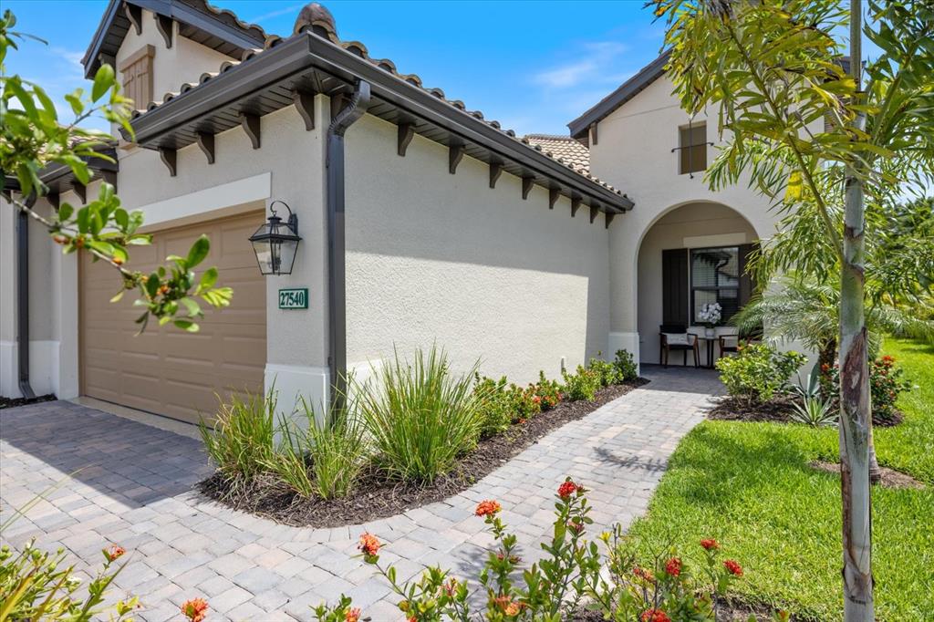 A paved walkway leads to the entrance of a house with a tan garage door — 27540 JANZEN COURT, ENGLEWOOD, FL
