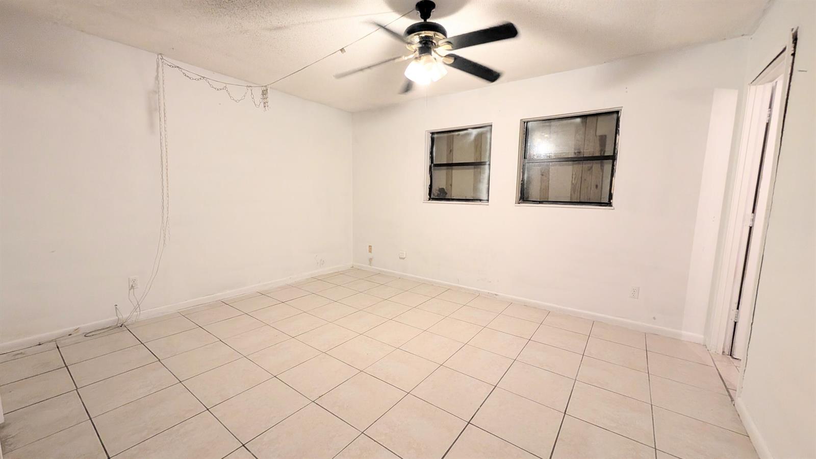 An empty room with white walls, tiled flooring, and a ceiling fan — 455 Janice Avenue, South Bay FL 33493, SOUTH BAY, FL