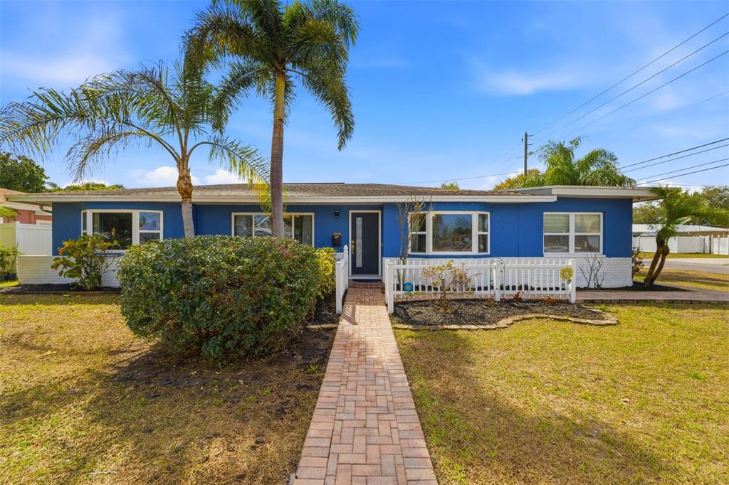 A blue single-story house features a brick walkway, a palm tree, and a white fence — 3998 22ND AVENUE N, ST PETERSBURG, FL