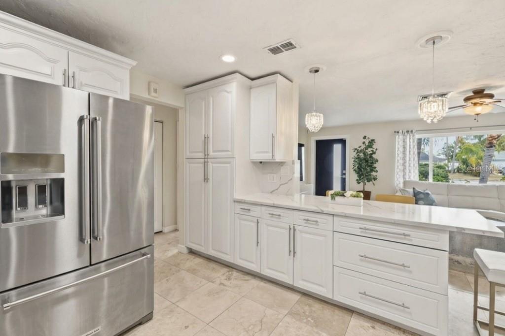 A modern kitchen features white cabinets, stainless steel appliances, and a marble-topped island — 3998 22ND AVENUE N, ST PETERSBURG, FL