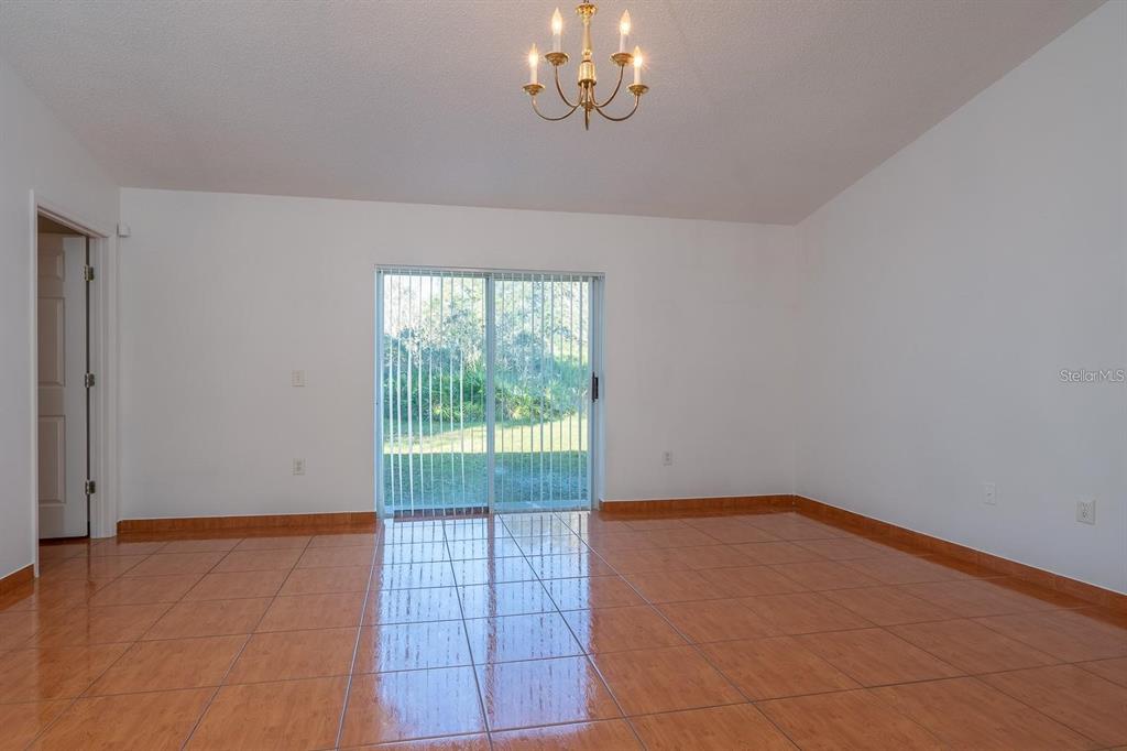 An empty room features glossy orange tile flooring, white walls, and a sliding glass door — 718 PINCON LANE, KISSIMMEE, FL