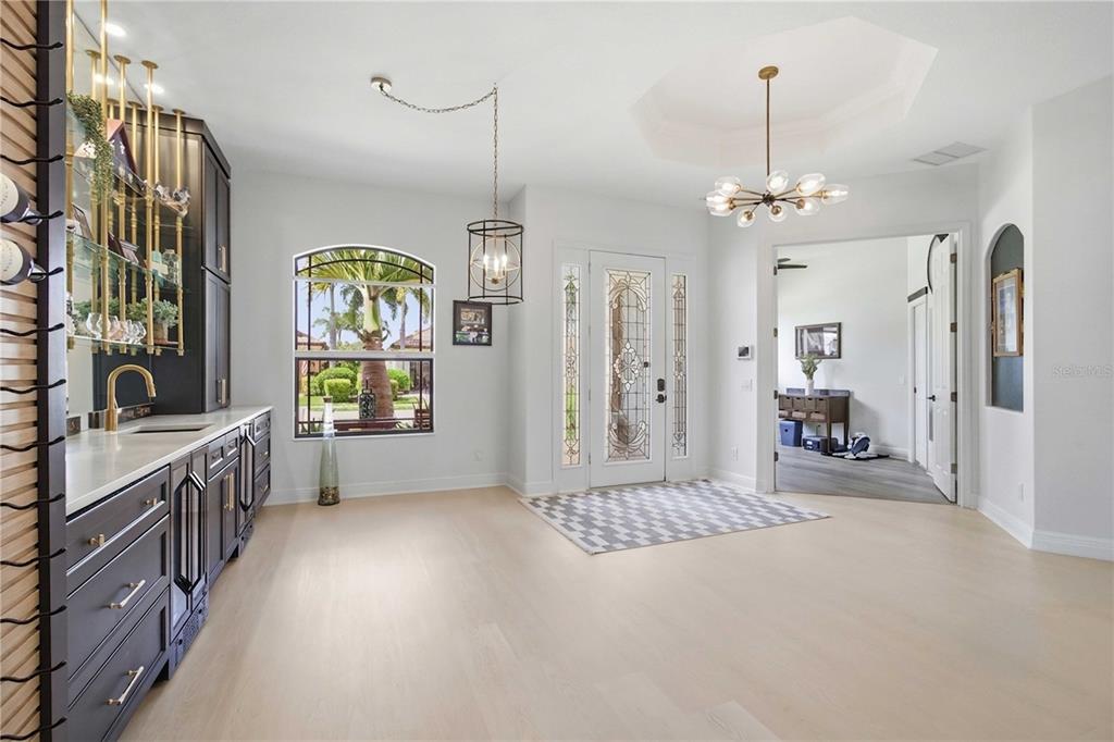 A foyer features light wood flooring, a dark wet bar, and a decorative glass front door — 8051 36TH STREET CIRCLE E, SARASOTA, FL