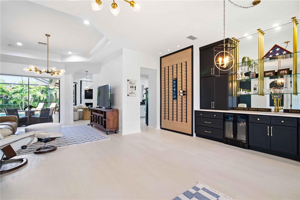 A living room features light wood floors, a built-in bar, and a wine rack wall — 8051 36TH STREET CIRCLE E, SARASOTA, FL