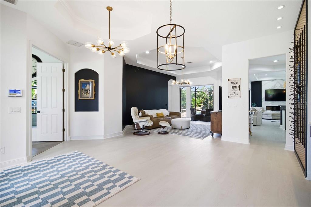 A spacious living room features white flooring, a black accent wall, and two modern chandeliers — 8051 36TH STREET CIRCLE E, SARASOTA, FL
