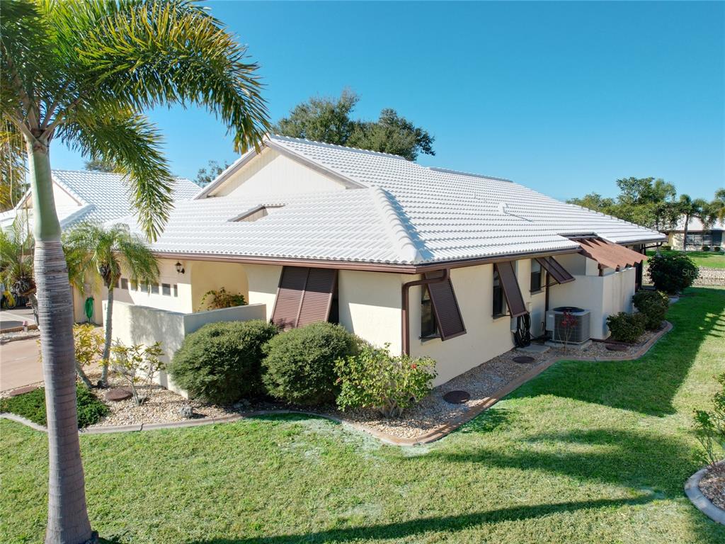 An exterior view of a single-story house with a white tile roof and brown shutters — 137 DRIFTING SANDS DRIVE, VENICE, FL
