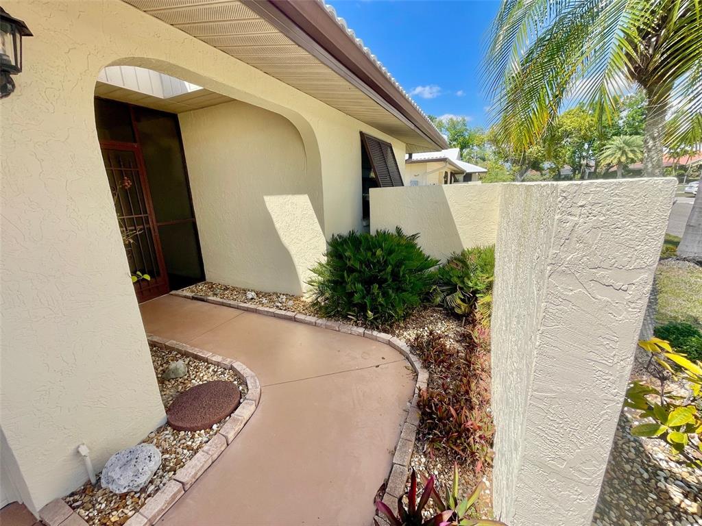 A curved concrete walkway leads to a covered entryway with a screen door and landscaping — 137 DRIFTING SANDS DRIVE, VENICE, FL