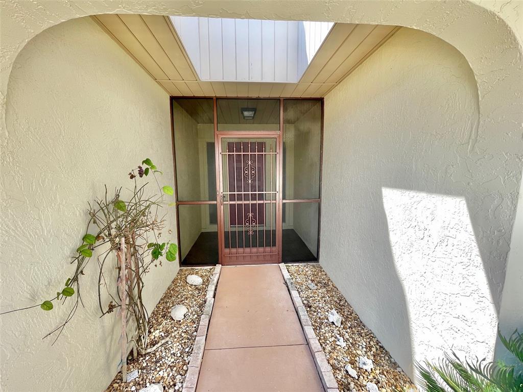A walkway leads to a front entrance with a screen door and a metal security gate — 137 DRIFTING SANDS DRIVE, VENICE, FL