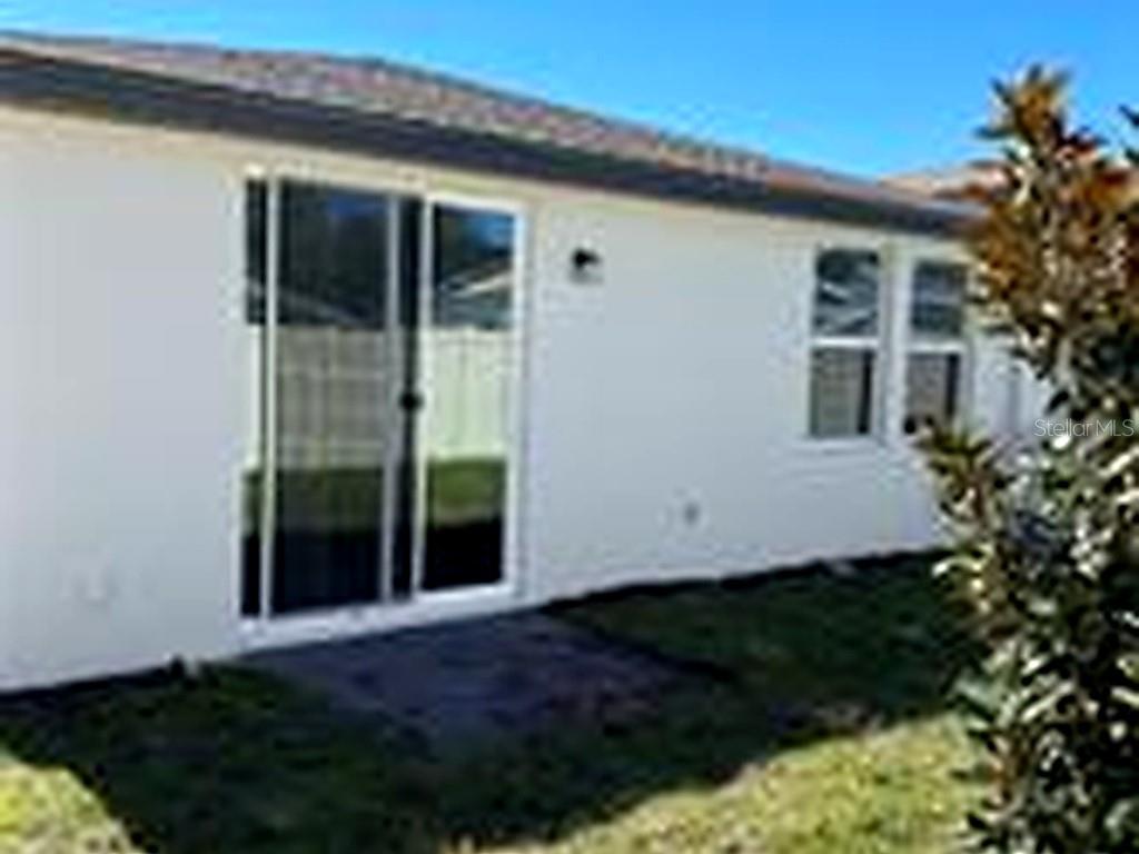 The exterior view shows a white house with a sliding glass door and two windows — 953 RIVERS CROSSING STREET, CLERMONT, FL