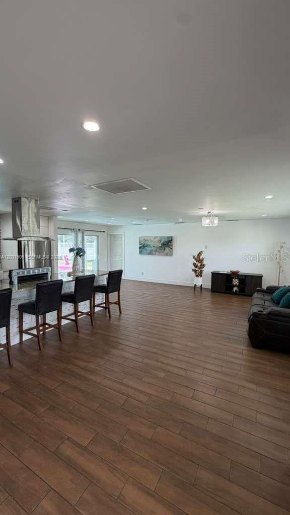 An open-concept living area features a kitchen island with bar seating and wood-look flooring — 244 SE 46TH ST, Cape Coral FL 33904, CAPE CORAL, FL