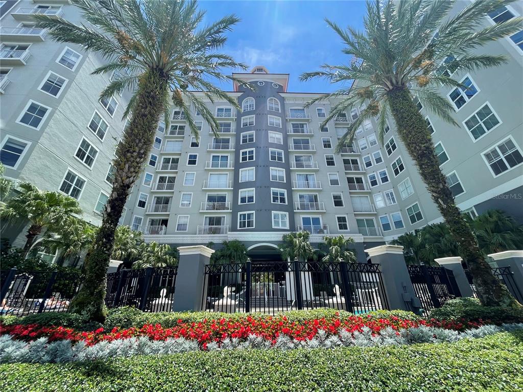 A low-angle view of a multi-story apartment building with palm trees and a garden — 700 S HARBOUR ISLAND BOULEVARD UNIT 110, TAMPA, FL