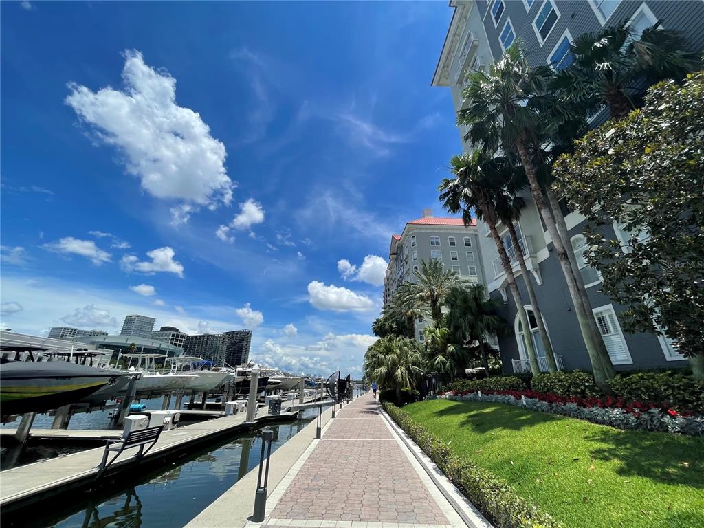 A black metal gate stands before a multi-story apartment building surrounded by palm trees — 700 S HARBOUR ISLAND BOULEVARD UNIT 110, TAMPA, FL