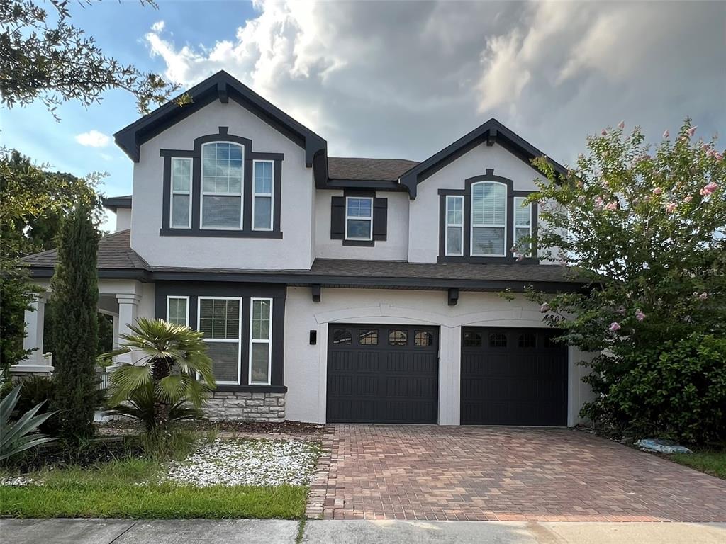 A two-story house with a two-car garage, stucco exterior, and a brick paver driveway — 4862 SOUTHLAWN AVENUE, ORLANDO, FL