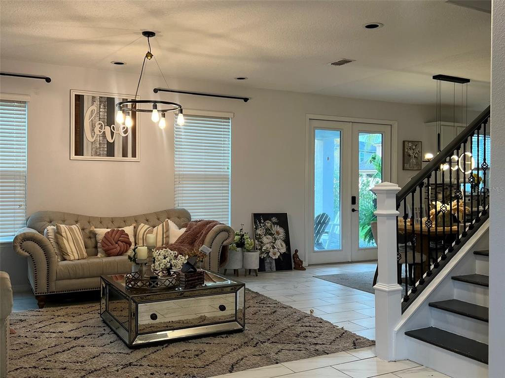 A living room features a tufted sofa, mirrored coffee table, and a staircase with railings — 4862 SOUTHLAWN AVENUE, ORLANDO, FL