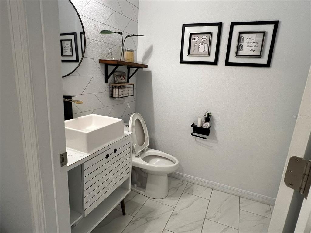A small bathroom features a white vessel sink, patterned wall tile, and a toilet — 4862 SOUTHLAWN AVENUE, ORLANDO, FL