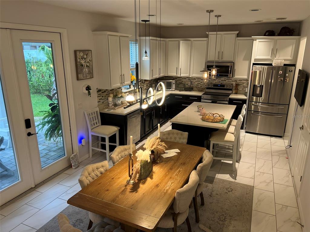 A kitchen with white upper cabinets, dark lower cabinets, a central island, and a dining table — 4862 SOUTHLAWN AVENUE, ORLANDO, FL