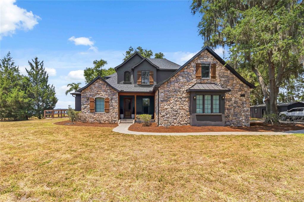 A two-story house with stone veneer, dark trim, and a front walkway on a lawn — 6805 BASS HIGHWAY, ST CLOUD, FL