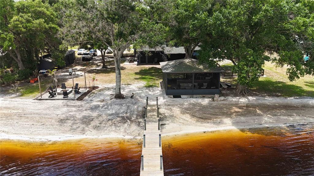 An aerial view of a wooden dock extending into a lake from a sandy shore — 6805 BASS HIGHWAY, ST CLOUD, FL