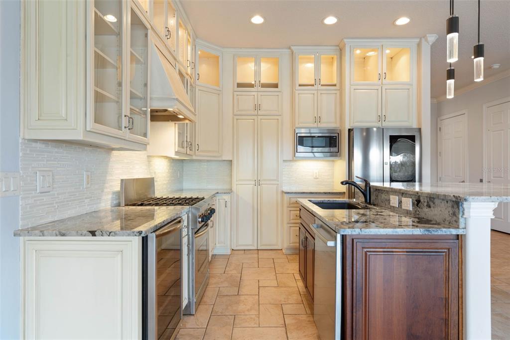 A kitchen features cream-colored cabinetry, granite countertops, stainless steel appliances, and a dark wood island — 262 YACHT HARBOR DRIVE, PALM COAST, FL