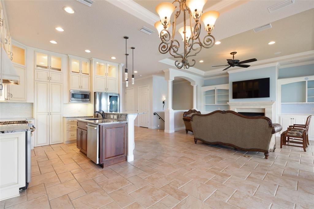An open-concept kitchen and living room featuring tile floors, white cabinetry, and a large chandelier — 262 YACHT HARBOR DRIVE, PALM COAST, FL