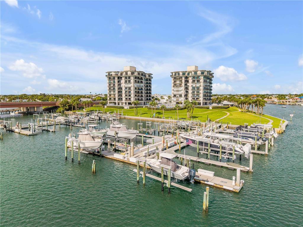 An aerial view shows a marina with several boats docked in front of two tall apartment buildings — 503 N CAUSEWAY UNIT 1020, NEW SMYRNA BEACH, FL
