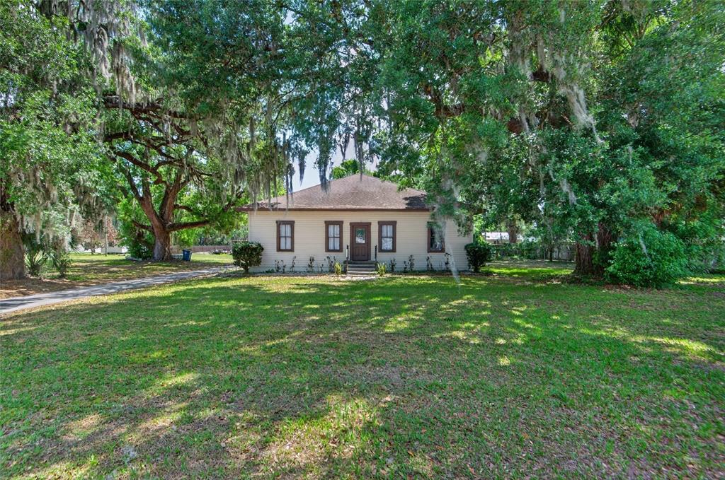 A single-story house with a hip roof sits on a large, tree-shaded grassy lot — 200 N ORANGE AVENUE, FORT MEADE, FL