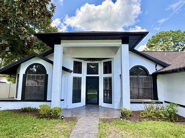 A white house with a dark roof and large windows features a prominent front entryway — 553 WALNUT GROVE PLACE, OVIEDO, FL