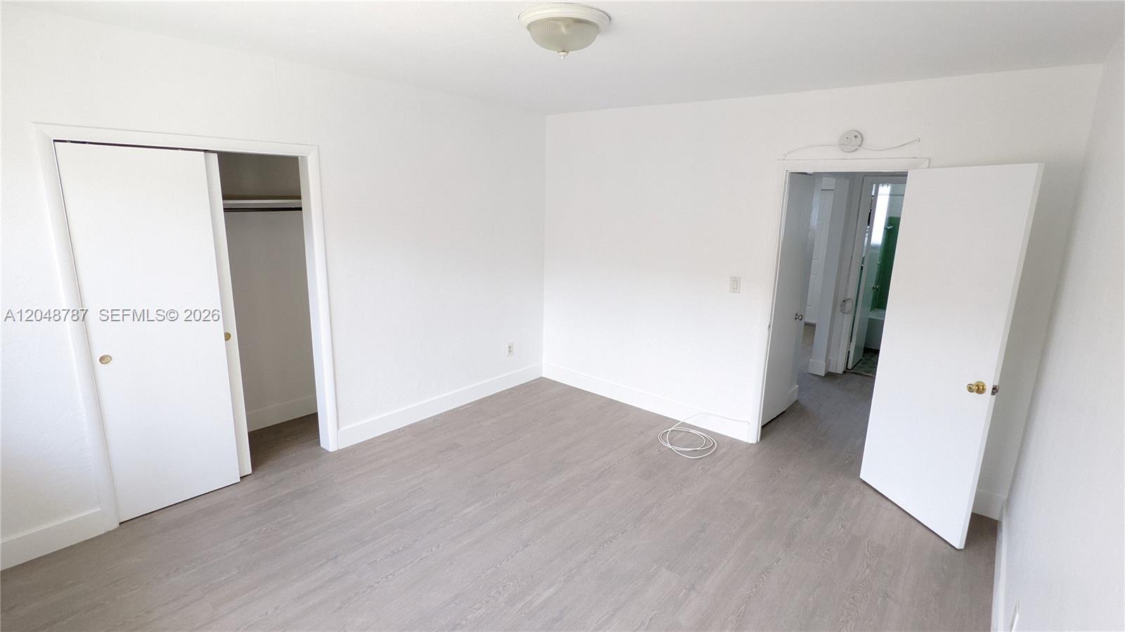 An empty bedroom features white walls, light wood-look flooring, a closet, and an open doorway — 811 81st St # 2, Miami Beach FL 33141, MIAMI BEACH, FL