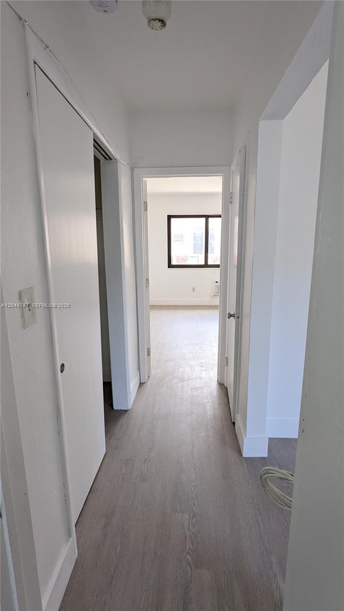 A narrow hallway with light wood-look flooring leads to a bedroom with a window — 811 81st St # 2, Miami Beach FL 33141, MIAMI BEACH, FL