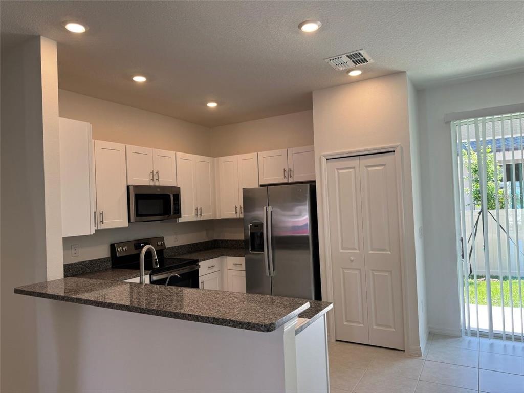 A kitchen with white cabinets, granite countertops, stainless steel appliances, and a breakfast bar — 10375 TRUMPET HONEYSUCKLE WAY, SAN ANTONIO, FL