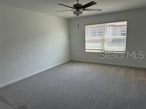 A bedroom with gray carpet, white walls, and a ceiling fan near a window — 10375 TRUMPET HONEYSUCKLE WAY, SAN ANTONIO, FL