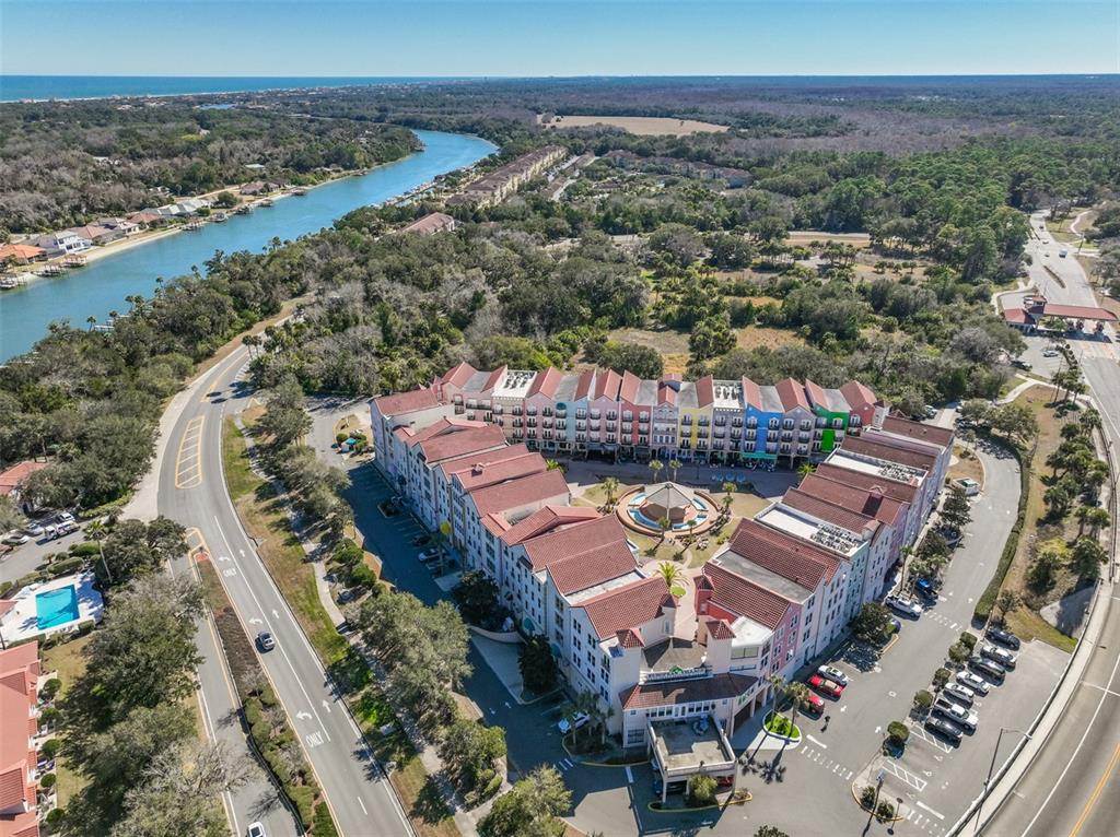 An aerial view shows a large, multi-colored apartment complex with red roofs near a waterway — 101 PALM HARBOR PARKWAY UNIT B414, PALM COAST, FL