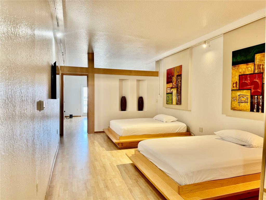 A bedroom features two platform beds, light wood flooring, and decorative wall art — 101 PALM HARBOR PARKWAY UNIT B414, PALM COAST, FL